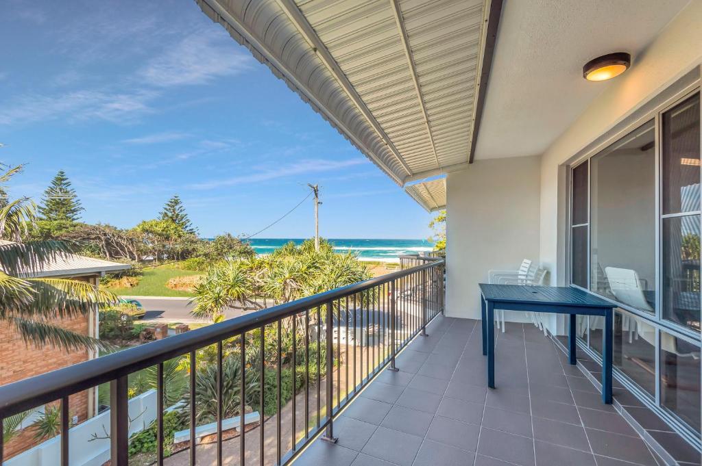 a balcony with a blue table and a view of the ocean at Wintersview 2 - Lennox Head in Lennox Head