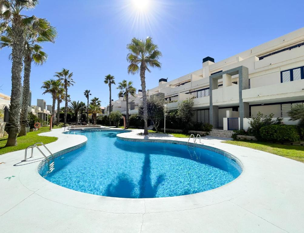 a large swimming pool with palm trees in front of a building at Breathtaking Apartment in Torrevieja