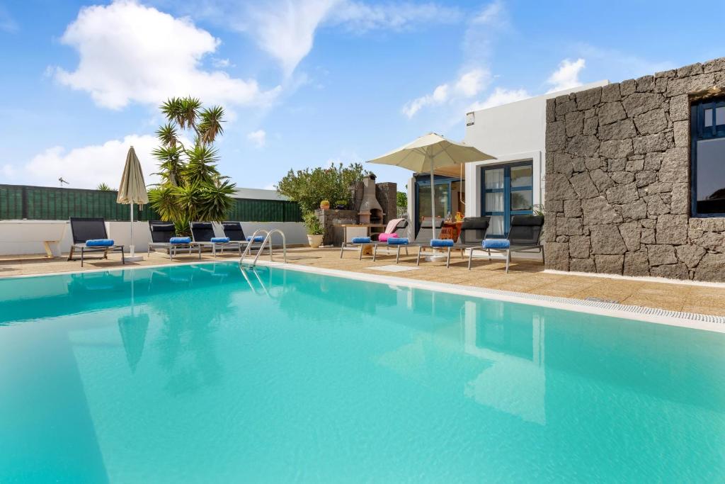 a swimming pool with blue water in front of a building at Lanzarote Villa Irina Marina Rubicón in Playa Blanca