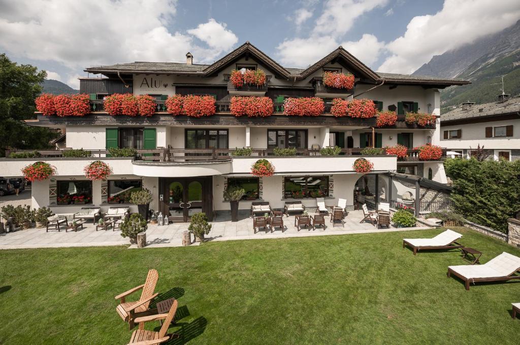 a large building with tables and chairs in a yard at Hotel Alù Mountain Design in Bormio