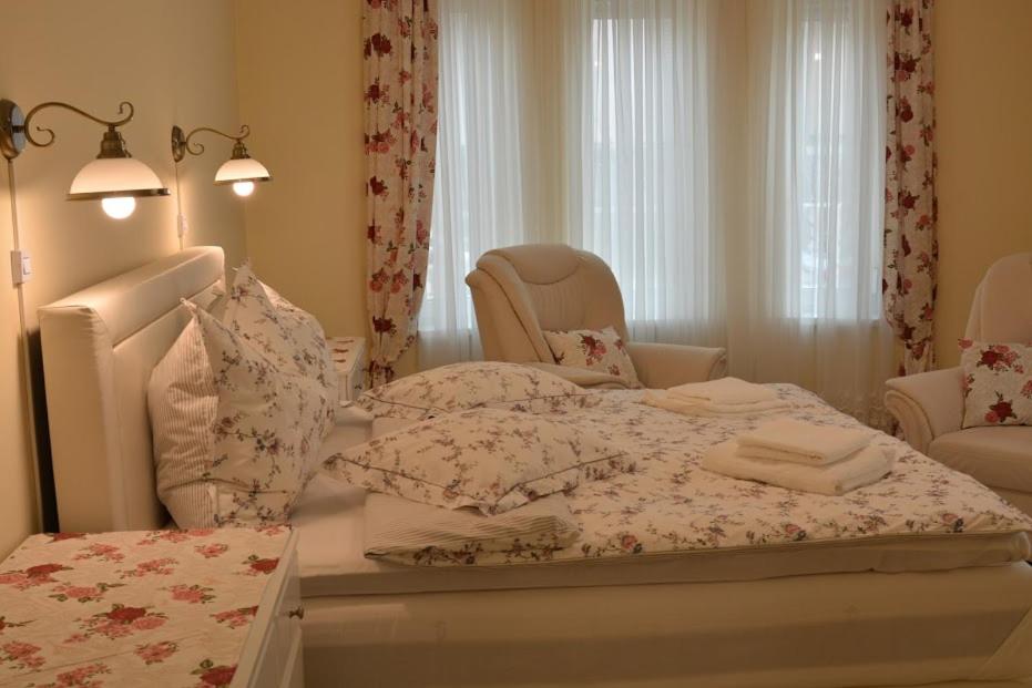 a bedroom with a bed with pillows and a chair at Aranyosház-Vendégház in Budapest