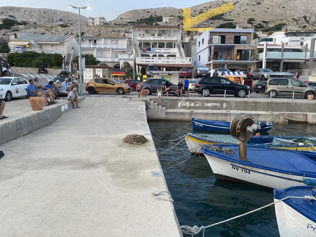 a group of people sitting on a dock with boats in the water at Pipe in Metajna