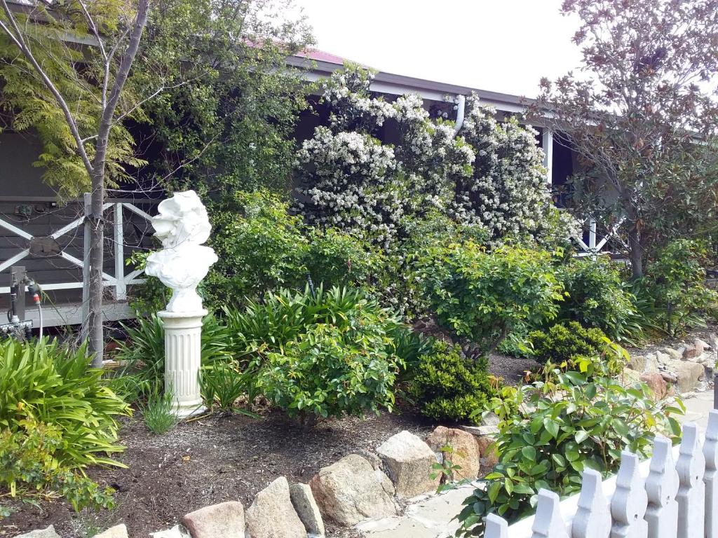 a white statue in a garden next to a white fence at Wagin Cottage Garden Bed and Breakfast in Wagin