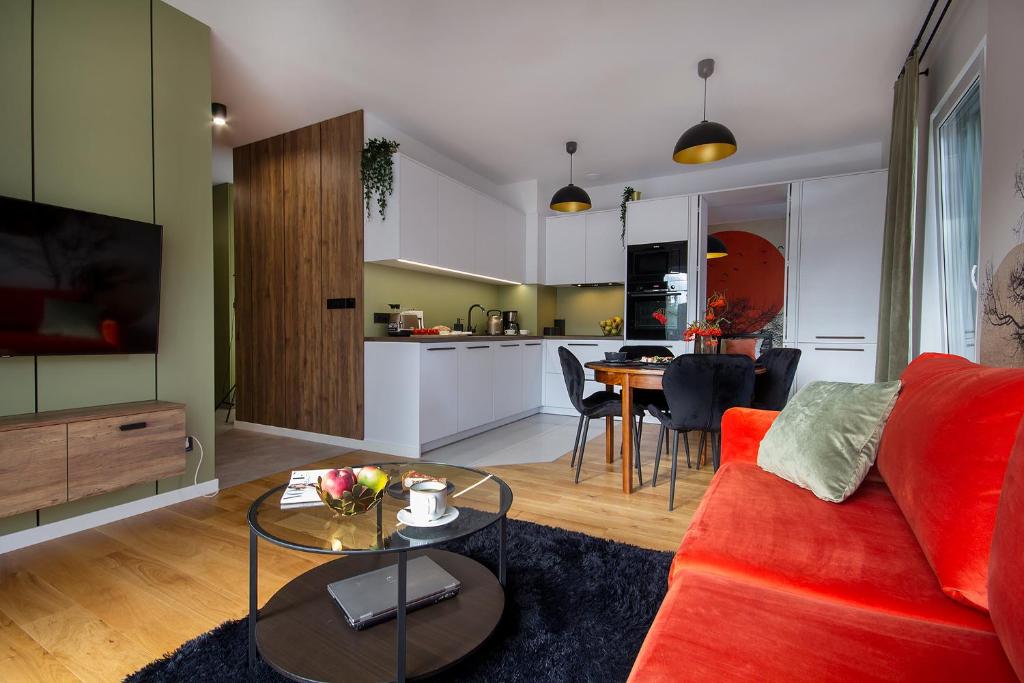 a living room with a red couch and a kitchen at W&K Apartments - Balance Suite in Koszalin
