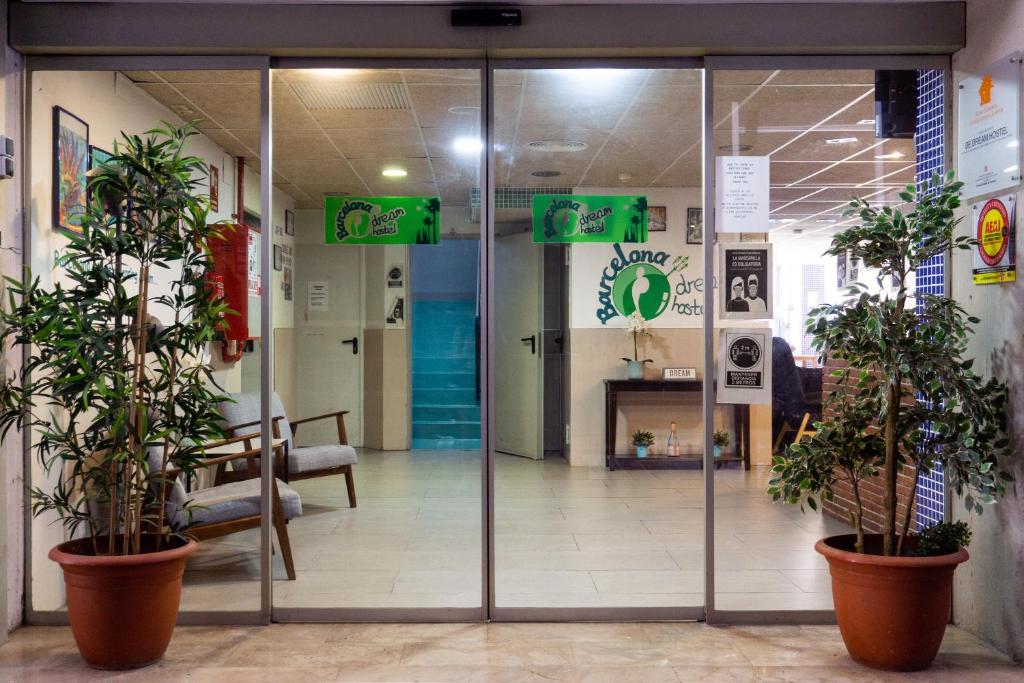Una puerta de vidrio en el vestíbulo de un hospital con plantas en macetas. en Be Dream Hostel, en Badalona
