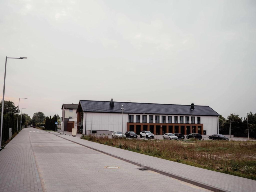 a large white building with cars parked in a parking lot at Hotel Angie in Puszczykowo