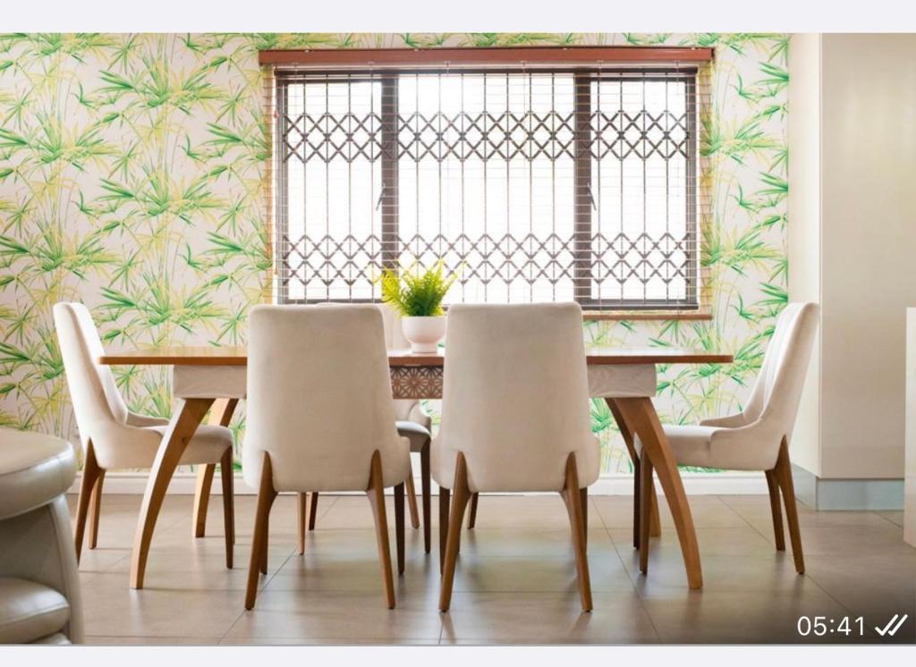 una sala da pranzo con tavolo, sedie e una finestra di Precious Paradise Villa ad Amanzimtoti