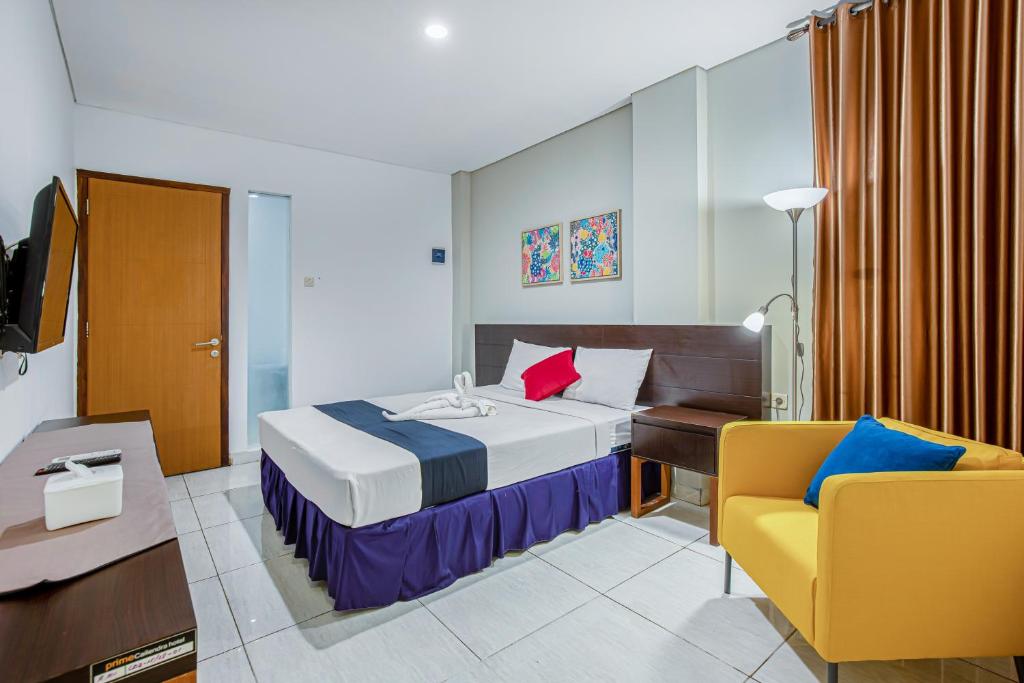 ジョグジャカルタにあるSans Hotel Prime Cailendra Yogyakarta by RedDoorzのベッドと椅子付きのホテルルーム