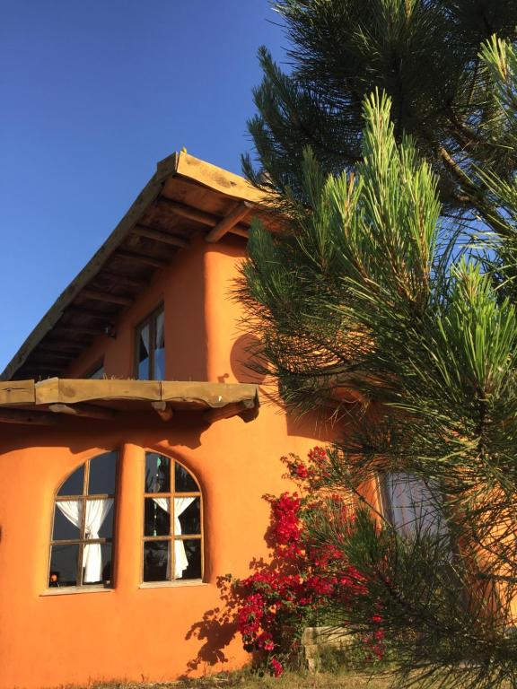 an orange house with a tree in front of it at Malva Rosa Relax La Juanita in José Ignacio