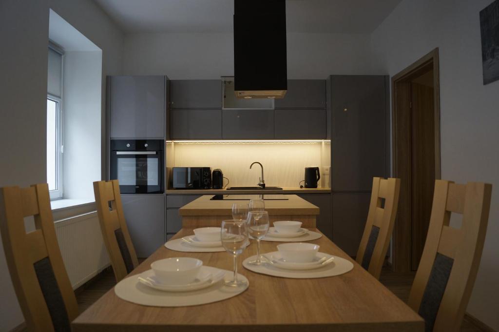 a kitchen with a wooden table with plates and wine glasses at Apartamenty Sokola in Łódź