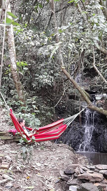 a person laying in a hammock next to a waterfall at Colibamboo Ecolodge Biocasa artesanal rodeada de naturaleza con jaccuzi y mucho más in Pacho