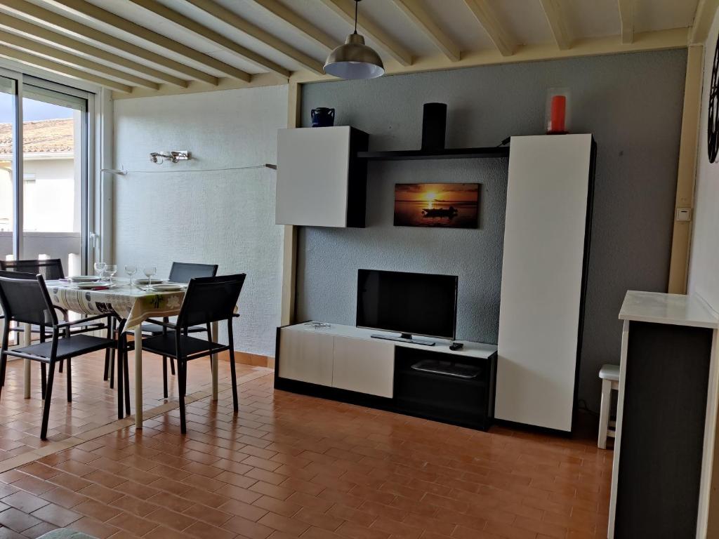 une salle à manger avec une table avec des chaises et une télévision dans l'établissement Plein sud 142, climatisé, à Argelès-sur-Mer