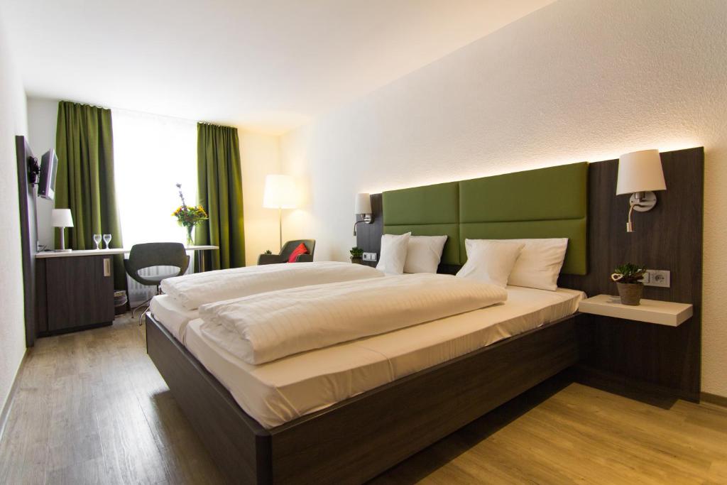 a bedroom with a large bed with a green headboard at Insel-Hotel-Lindau in Lindau