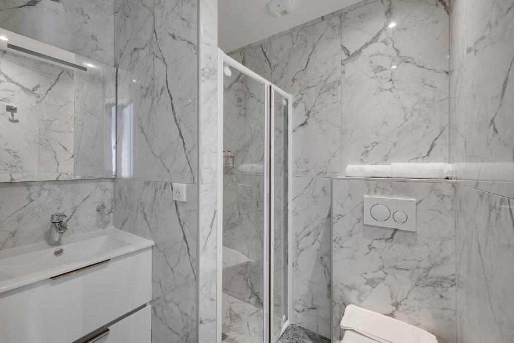 a white bathroom with a shower and a sink at Le Bellevue in Paris