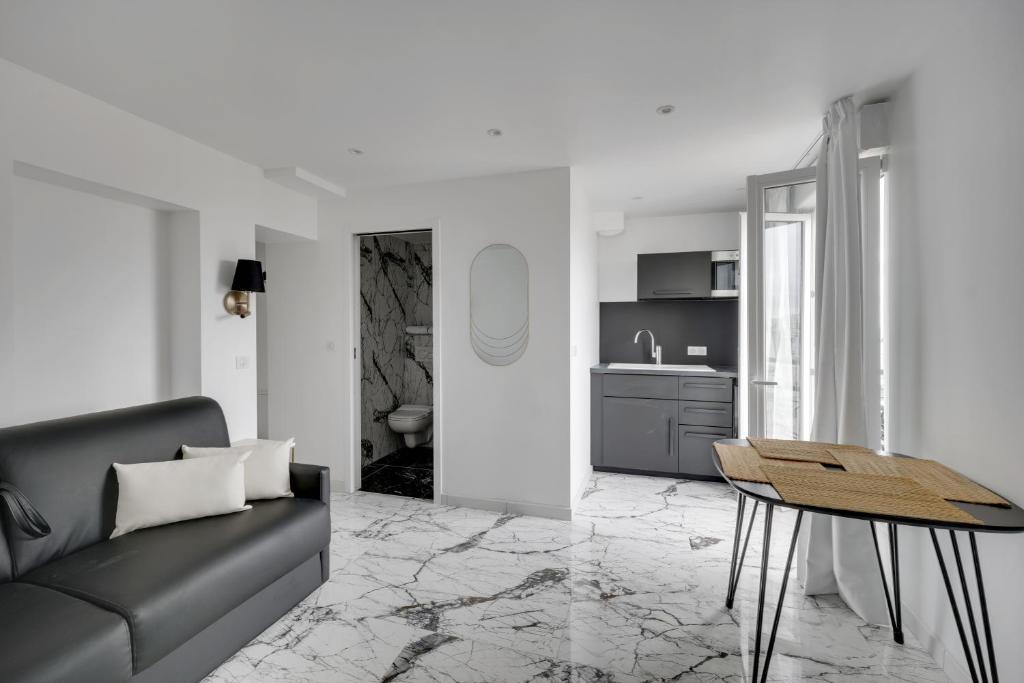 uma sala de estar com um sofá e uma mesa em Le Bellevue em Paris