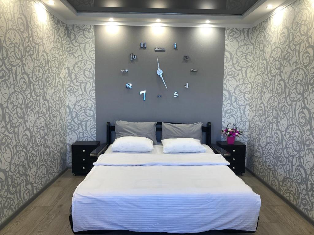 a bedroom with a large bed with a clock on the wall at Сдам посуточно однакомнатную квартиру in Kharkiv