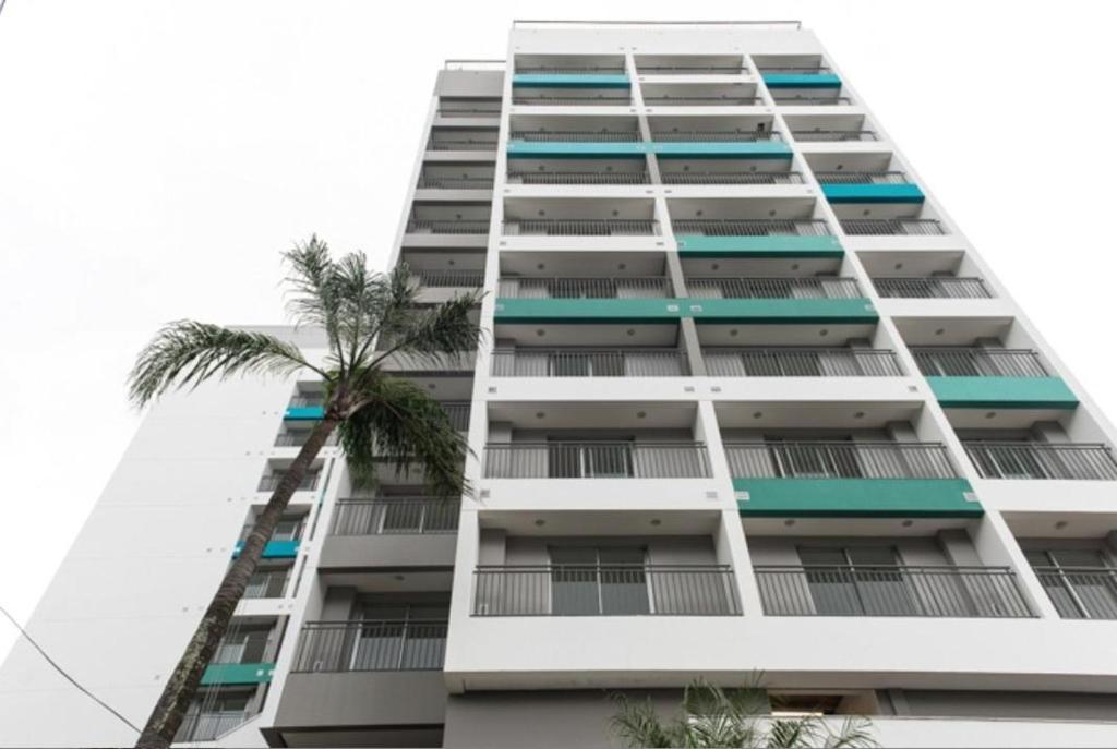 un edificio de apartamentos alto y blanco con una palmera en Flat WiseSP - Expo Anhembi, en São Paulo