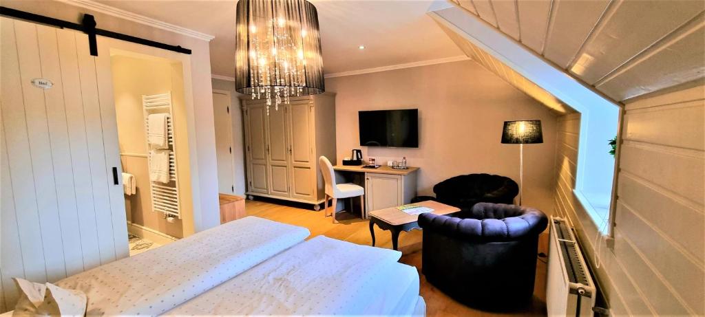 a bedroom with a bed and a chair and a desk at Hotel Eifelland in Butgenbach