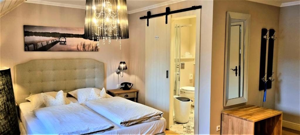 a bedroom with a bed with white sheets and a chandelier at Hotel Eifelland in Butgenbach