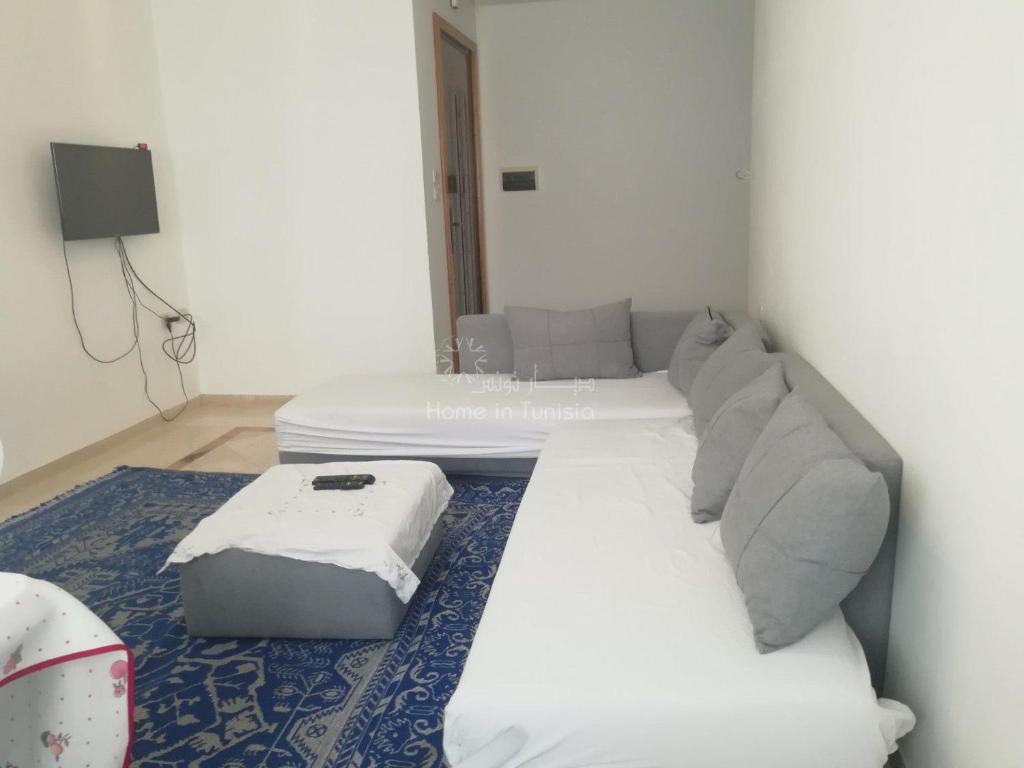 a bedroom with a white bed and a couch at Joli appartement s+2 hammem sousse in Sousse