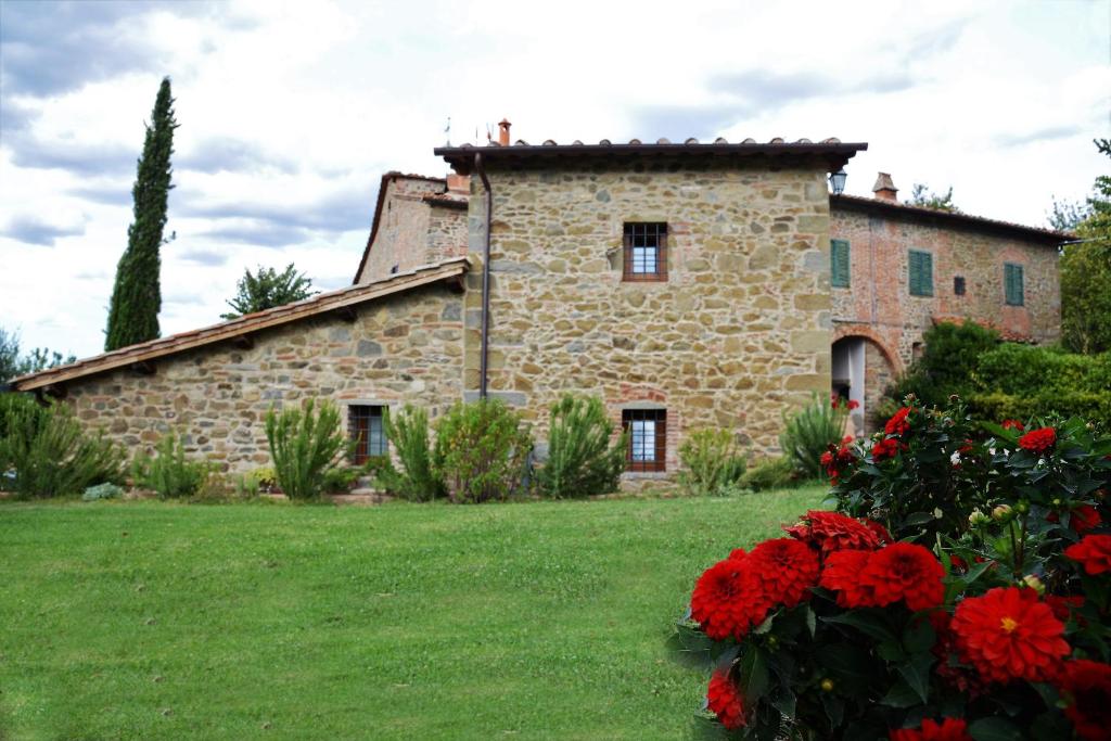 カヴリーリアにあるCottage indipendente di 70 mq con piscina ad uso esclusivo , aria condizionata , 2 bagni , living room ,ampia cucina , lavanderia , terrazza ,giardini , parcheggio privato immerso nelle colline toscane facente parte di dimora storica toscana di fine 1700の赤い花の古い石造りの家