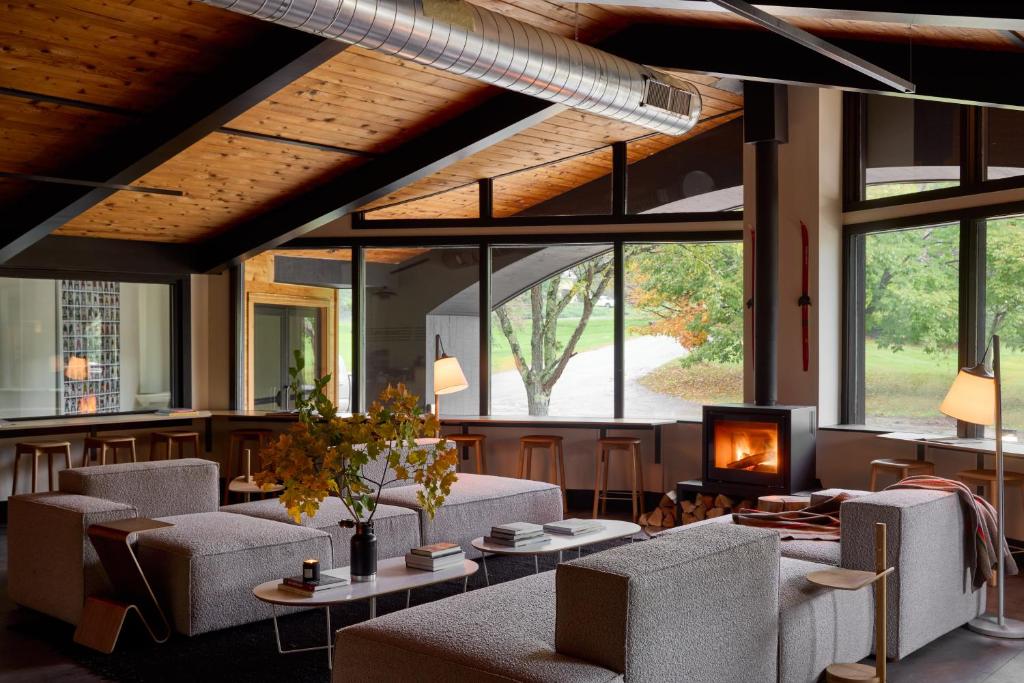 a lobby with couches and a fireplace and windows at Tälta Lodge, a Bluebird by Lark in Stowe
