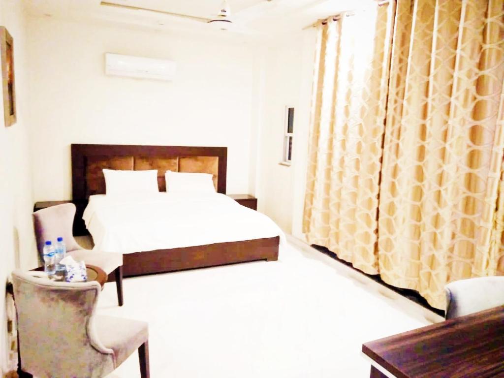 ラホールにあるJade Dragon Hotel DHA Lahoreのベッド、テーブル、椅子が備わるホテルルームです。