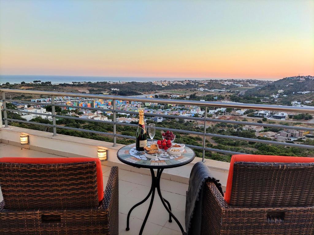 een tafel met een fles wijn en 2 stoelen op een balkon bij AlbufeiraOrada SunSet Penthouse by Be Cherish in Albufeira