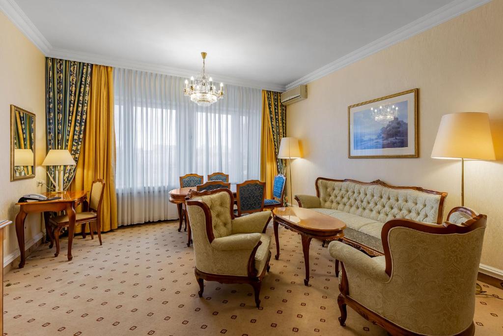a hotel room with a couch and a table and chairs at Natsionalny Hotel in Kyiv