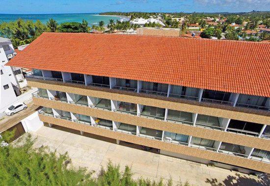 un edificio de apartamentos con techo naranja y el océano en Praia dos Carneiros Flat Hotel Apto Completo en Tamandaré