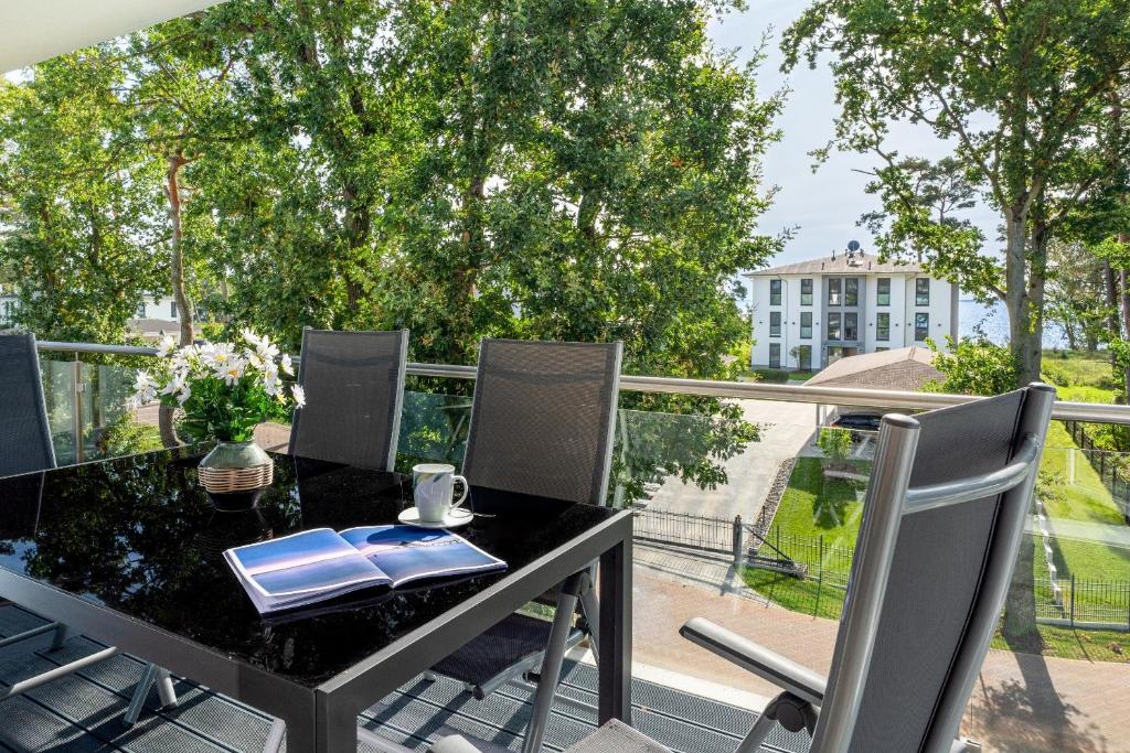 een zwarte tafel en stoelen op een balkon met uitzicht bij Apartment "Haffblick" - Haffresidenz in Zirchow
