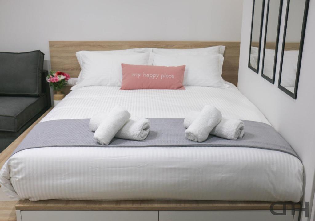 a bed with white sheets and a pink pillow on it at New deluxe studio 4 downtown Thessaloniki- Fully equiped in Thessaloniki