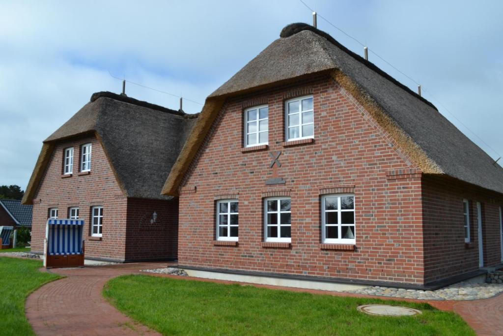 a large brick house with a thatched roof at Hotel Garni Sössaarep's Hüs in Nebel