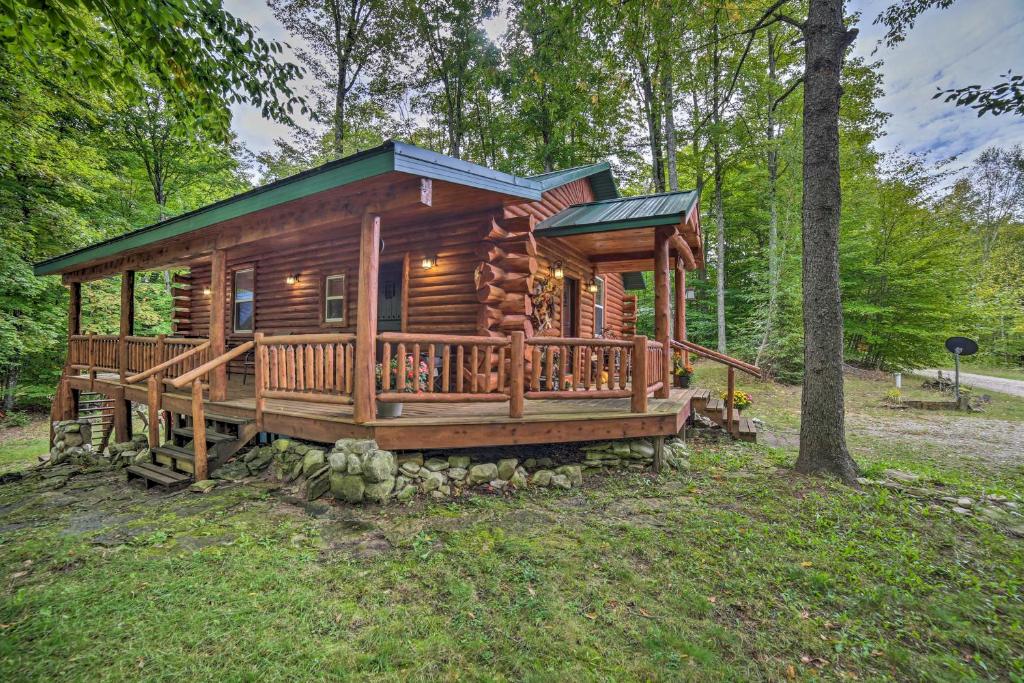 a cabin in the woods with a large deck at Updated Manistique Log Cabin, Yard and Fire Pit in Manistique