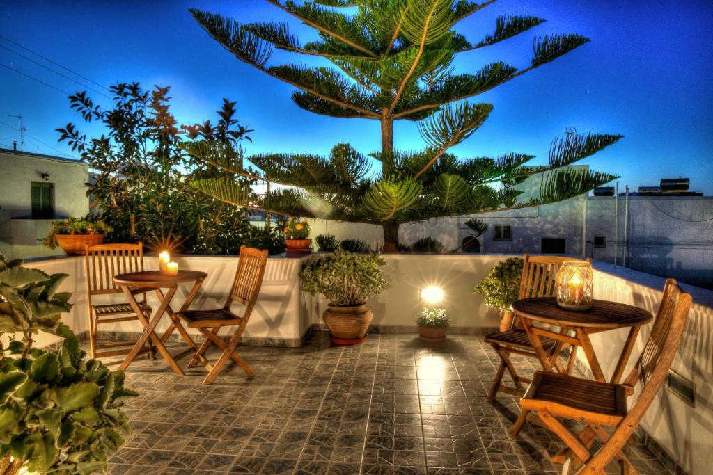 a patio with two tables and chairs and a palm tree at Pension Anna in Naousa