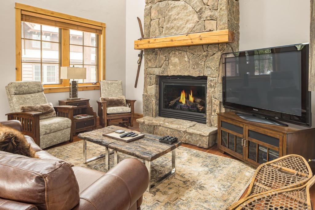a living room with a fireplace and a television at Lone Peak Townhome 5 in Big Sky