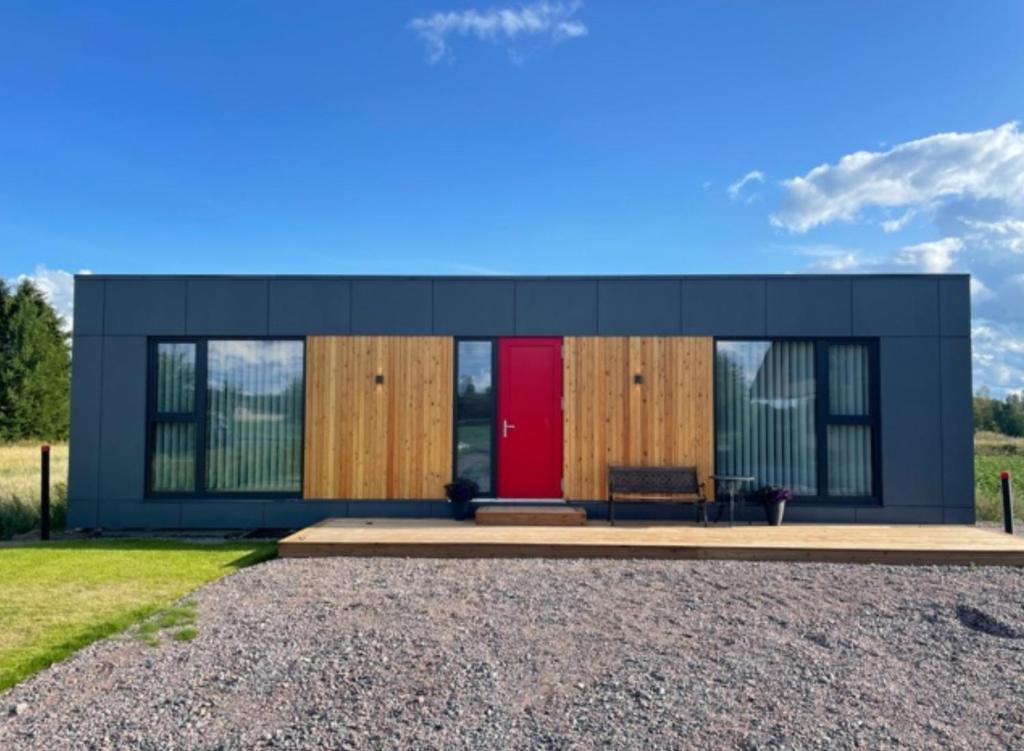 une petite maison avec une porte rouge dans une allée en gravier dans l'établissement Modern accommodation close to lake and nature, à Köyliö