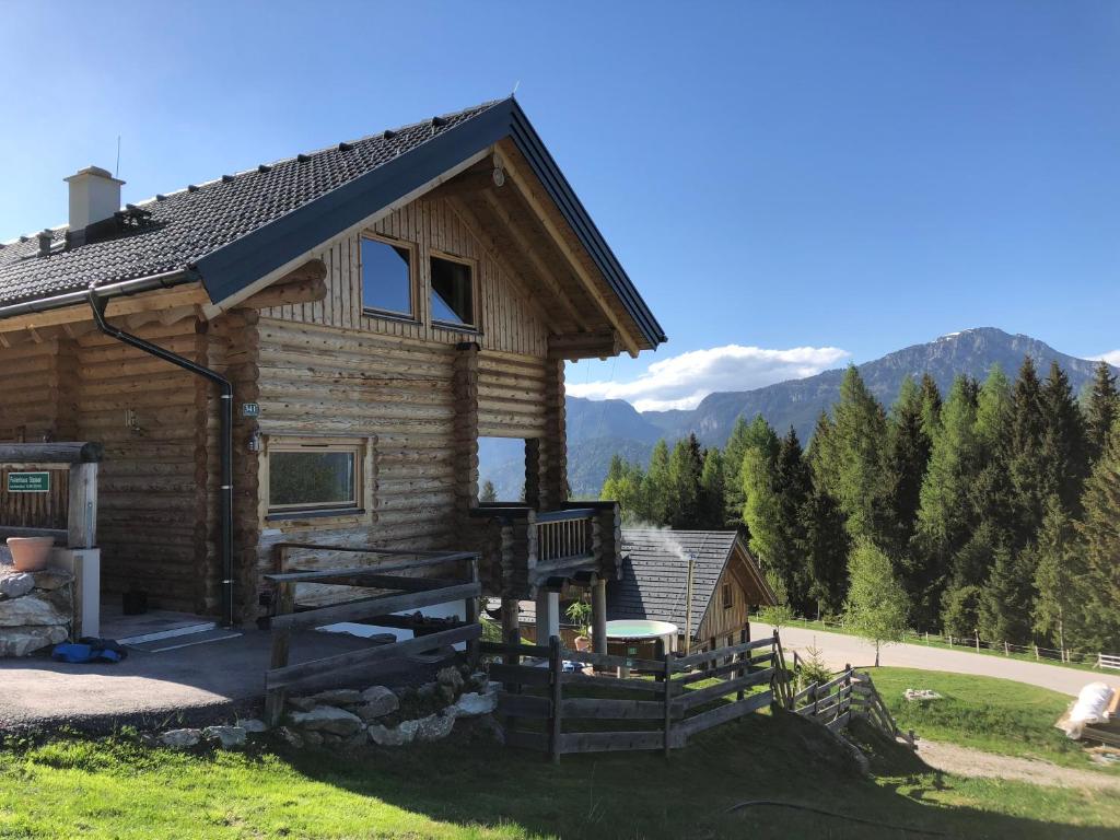 a log cabin with a porch and mountains in the background at Ferienhaus Stoiser in Pruggern