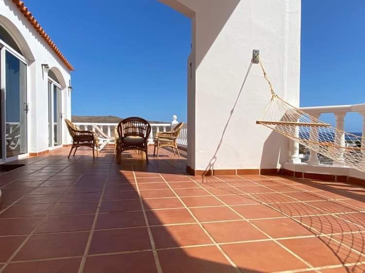 a porch with chairs and a hammock on a house at Sol y Mar in Tarajalejo