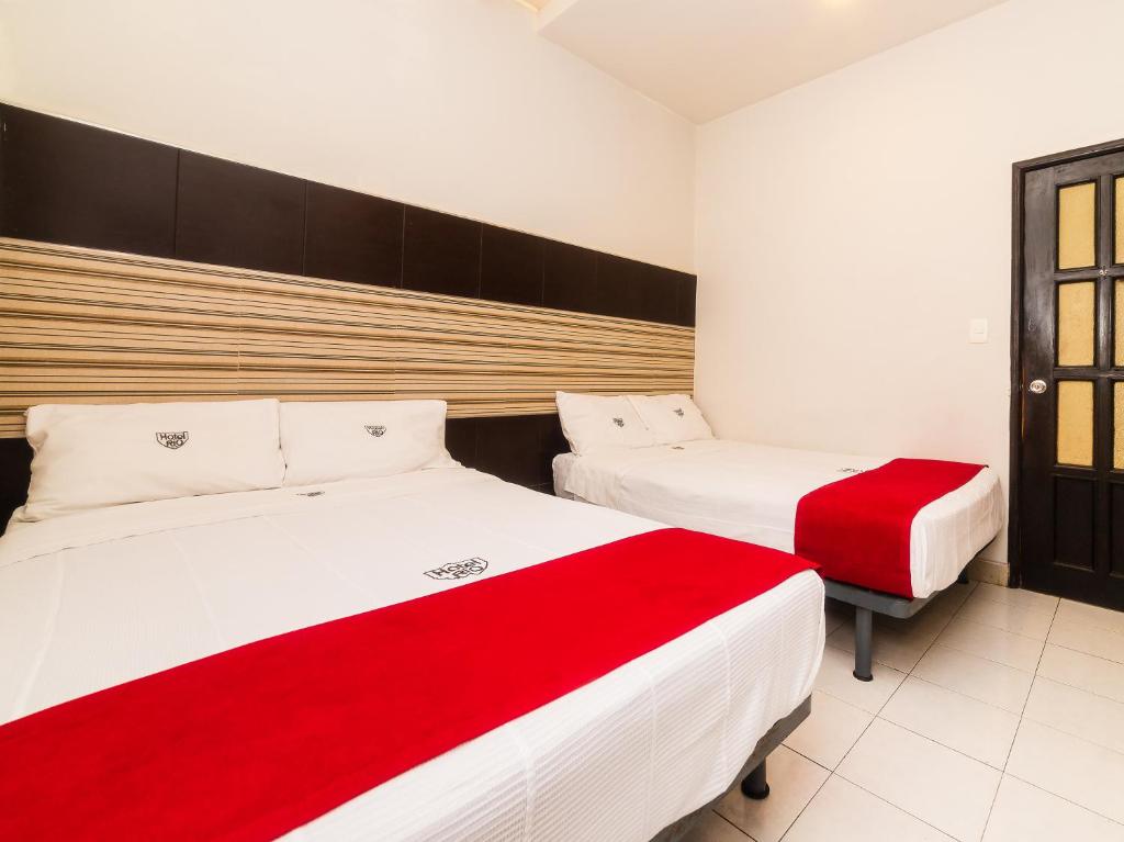two beds in a room with red and white sheets at Hotel Río in Puebla