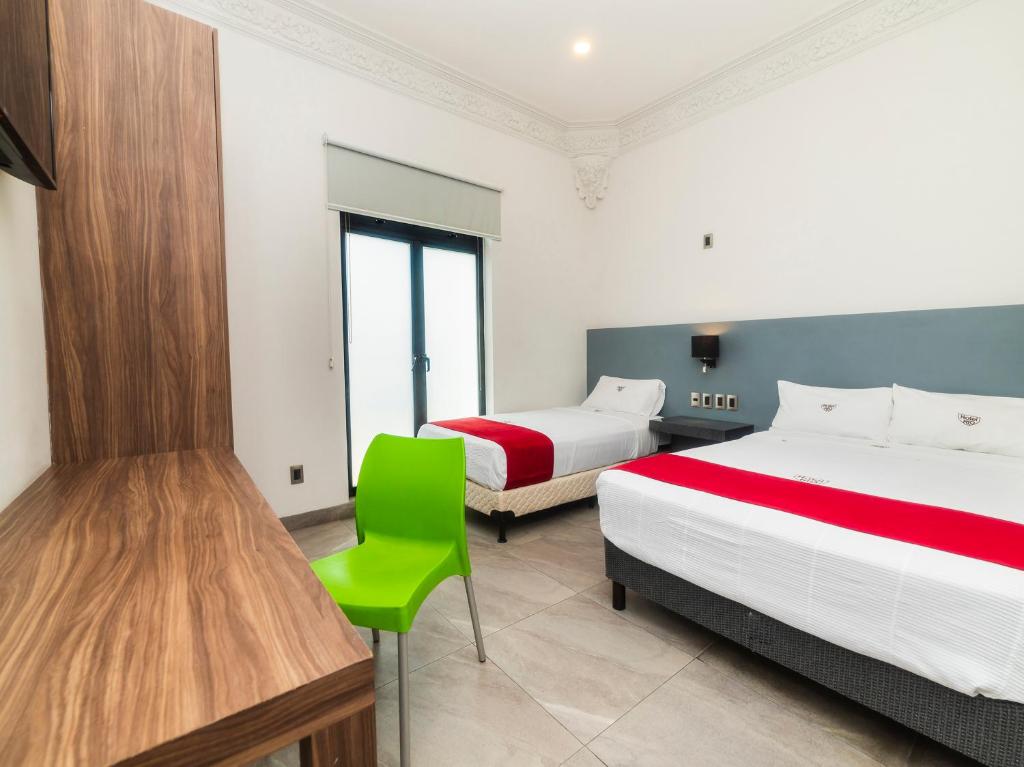 a bedroom with two beds and a green chair at Hotel Río Puebla Centro in Puebla