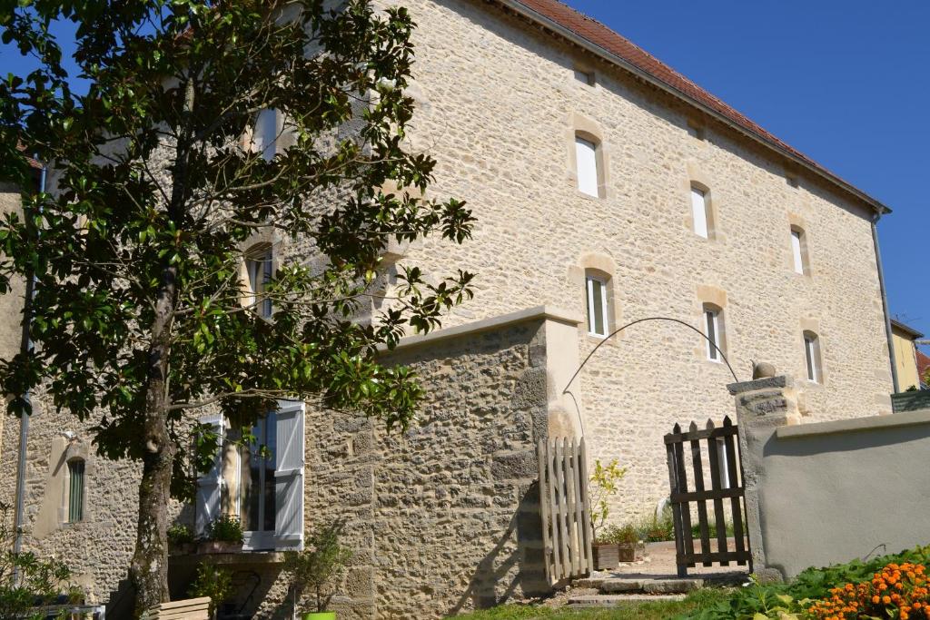 un grand bâtiment en briques avec un portail et un arbre dans l'établissement Chambres d'Hôtes Le Moulin à Epices, à Chargey-lès-Gray