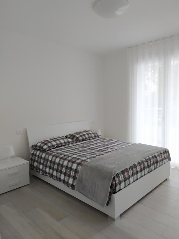 リド・ディ・イエゾロにあるJesolo Appartamenti F2 - Light Blueの白いベッドルーム(ベッド1台、ナイトスタンド付)