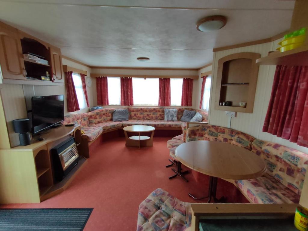 a living room with couches and a table and a tv at Coastfields Caravan Site Ingoldmells Sleeps 8 in Ingoldmells