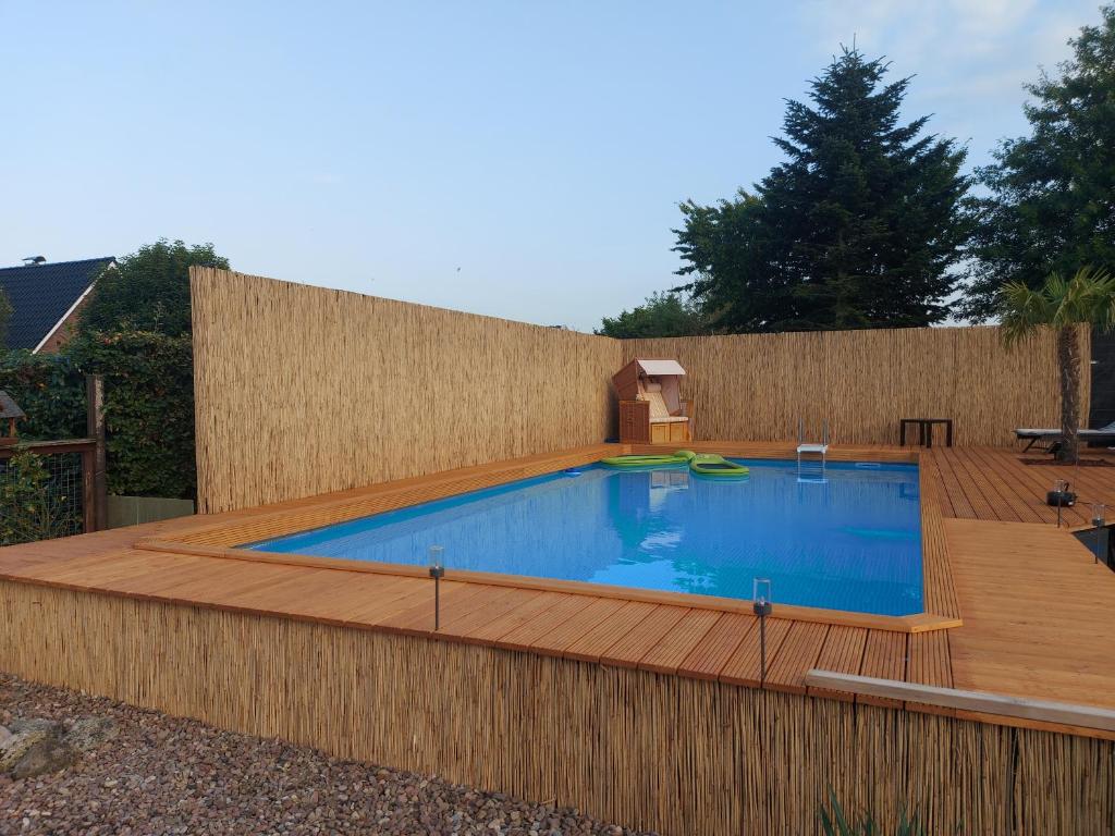 a swimming pool with a wooden deck and a fence at Ferienwohnung Uhlenbusch Paradise in Friesoythe