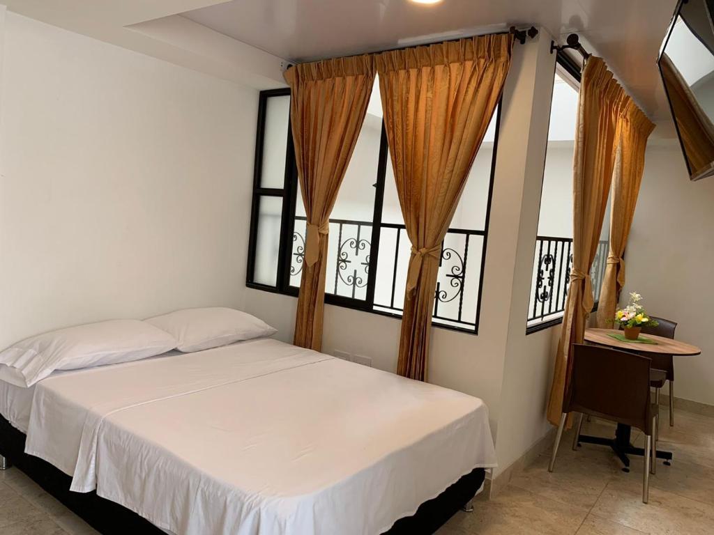 a bedroom with a white bed and two windows at Hostel Casa Zambrano in Popayan