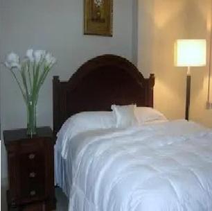 a bedroom with a white bed and a night stand with a vase of flowers at Hotel Premier Inn in Manta