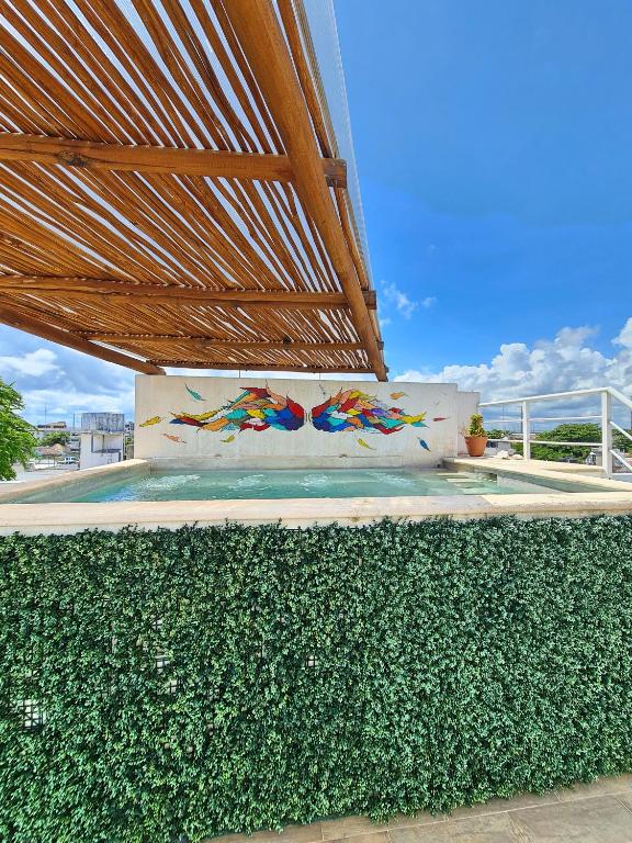 a wall with a painting on it next to a hedge at Playa Nah in Playa del Carmen