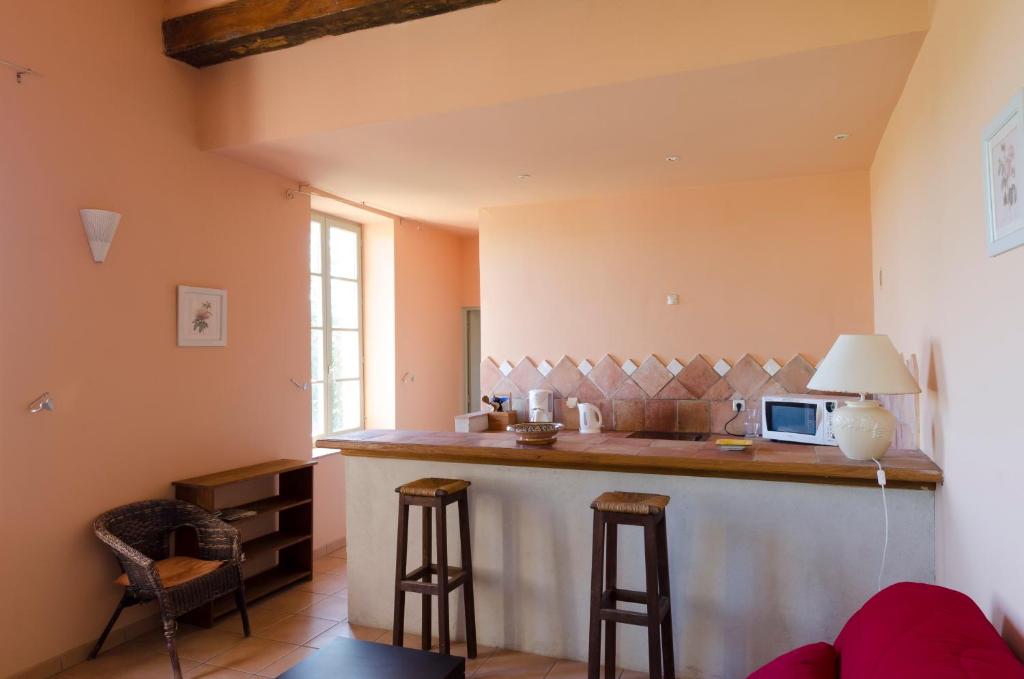 a kitchen with a bar with stools and a microwave at Château Pech-Celeyran in Salles-dʼAude