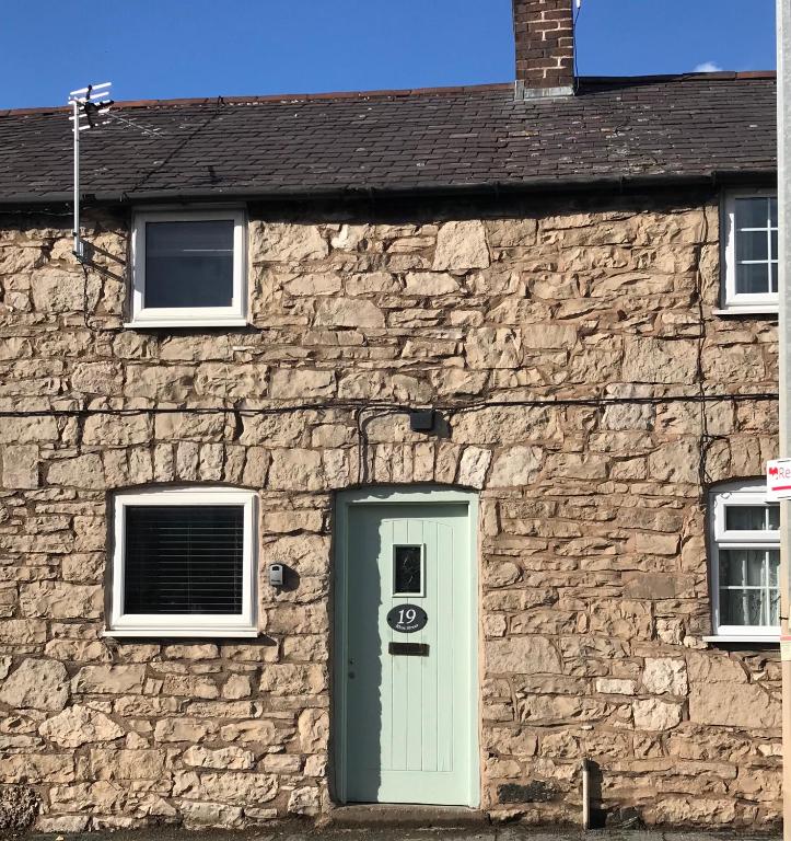 a stone building with a green door and windows at Rhos cottage Ruthin in Ruthin